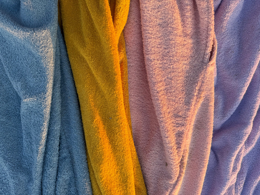 Close-up of three textured towels in purple, yellow, and blue.