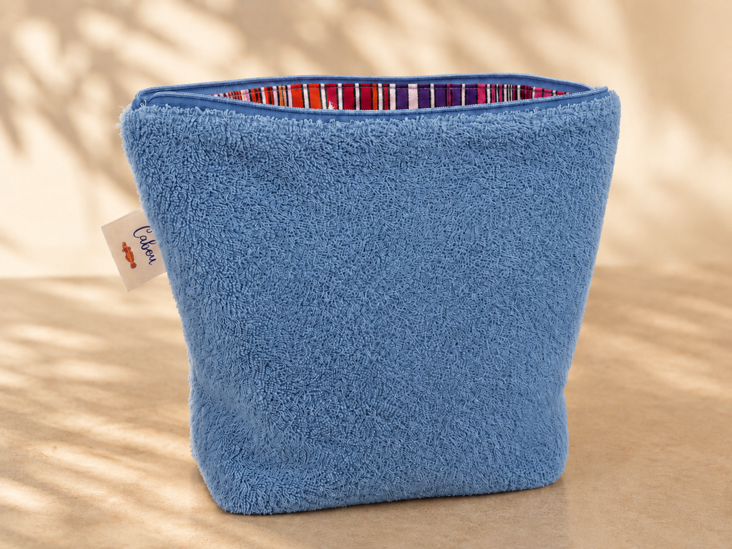 Blue towel with striped edge on a beige surface