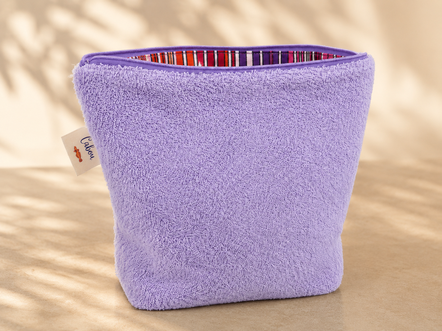 Purple textured pouch with a striped interior on a beige background
