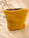 Yellow textured pouch with a striped lining on a beige background