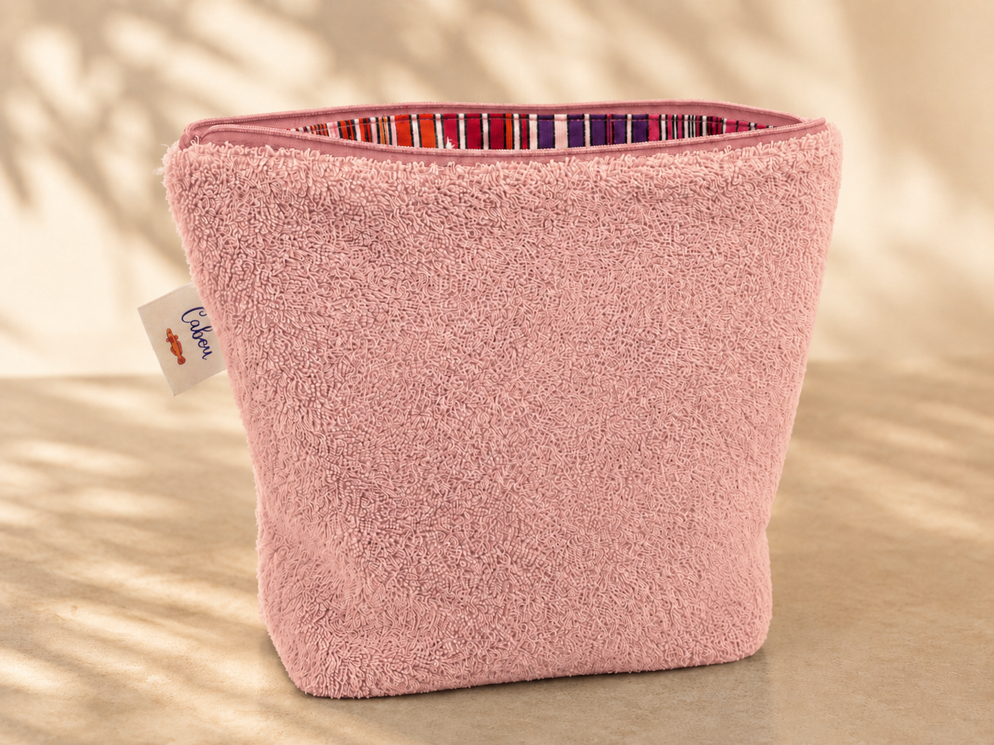 Pink textured basket with a colorful interior on a beige background