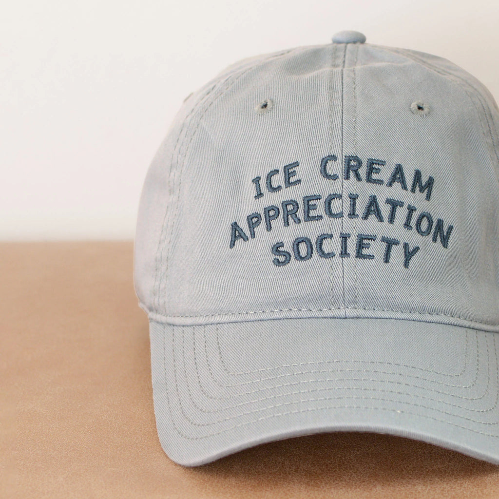 Light blue cap with 'Ice Cream Appreciation Society' text on a beige background